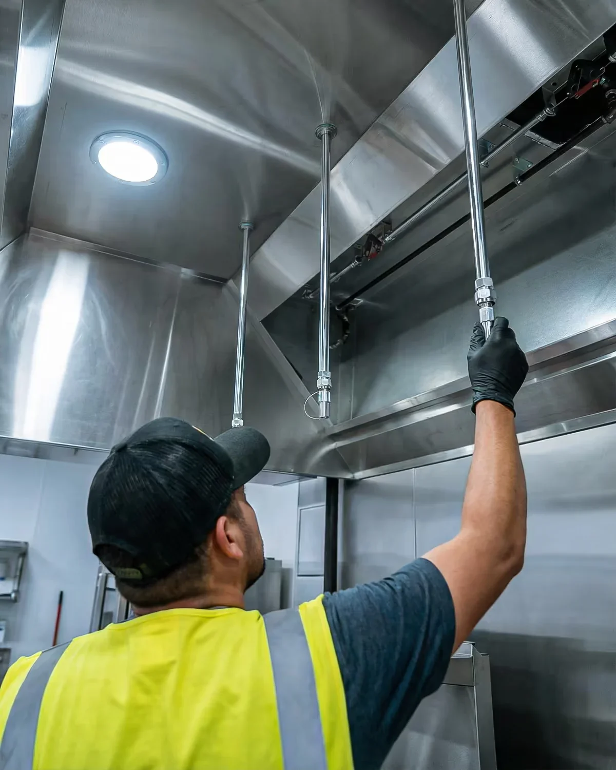 Technician inspecting equipment above a commercial kitchen hood
